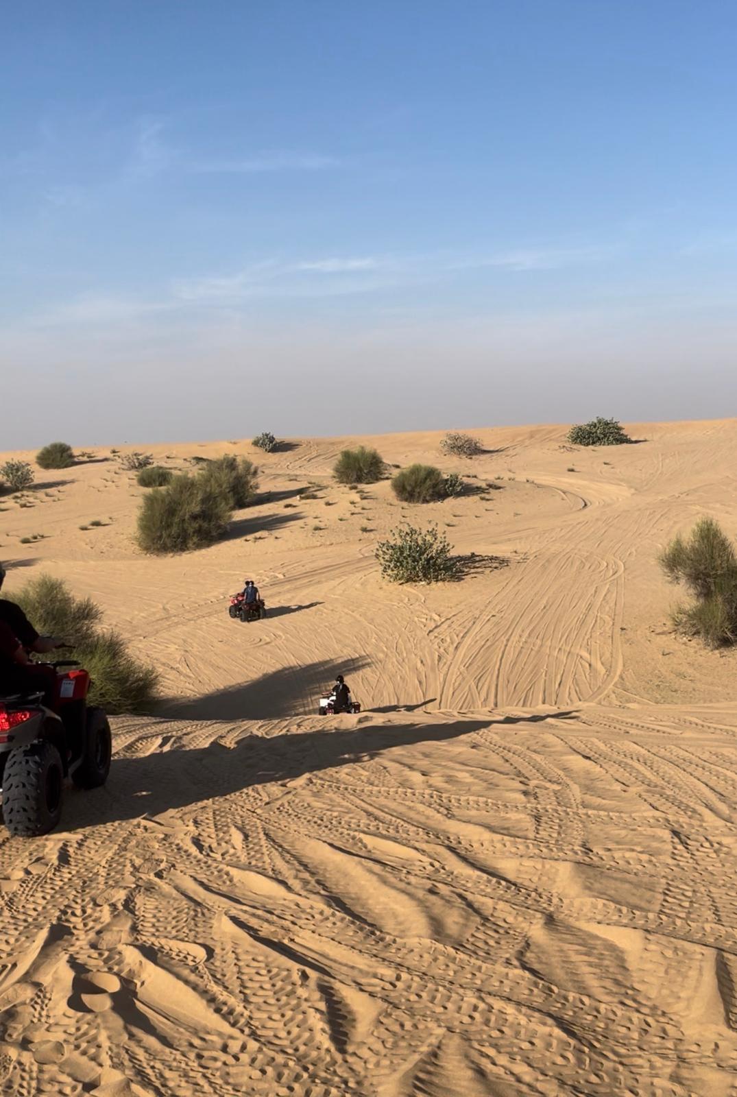 ATVs riding across vast golden desert dunes in Dubai